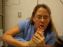 A nerdy woman in a nursing costume licks her toes while being filmed on camera.